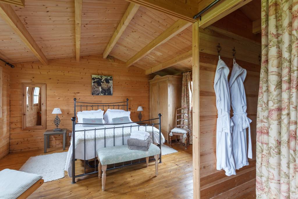 Garden cabin bedroom with timber-clad walls and iron bed
